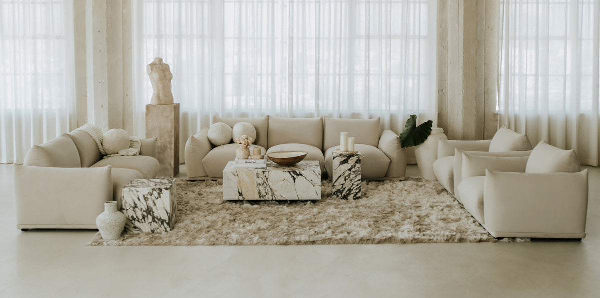 Luxury sofa in premium fabric finish paired with a vintage leather sofa, styled with layered rugs and modern lighting.