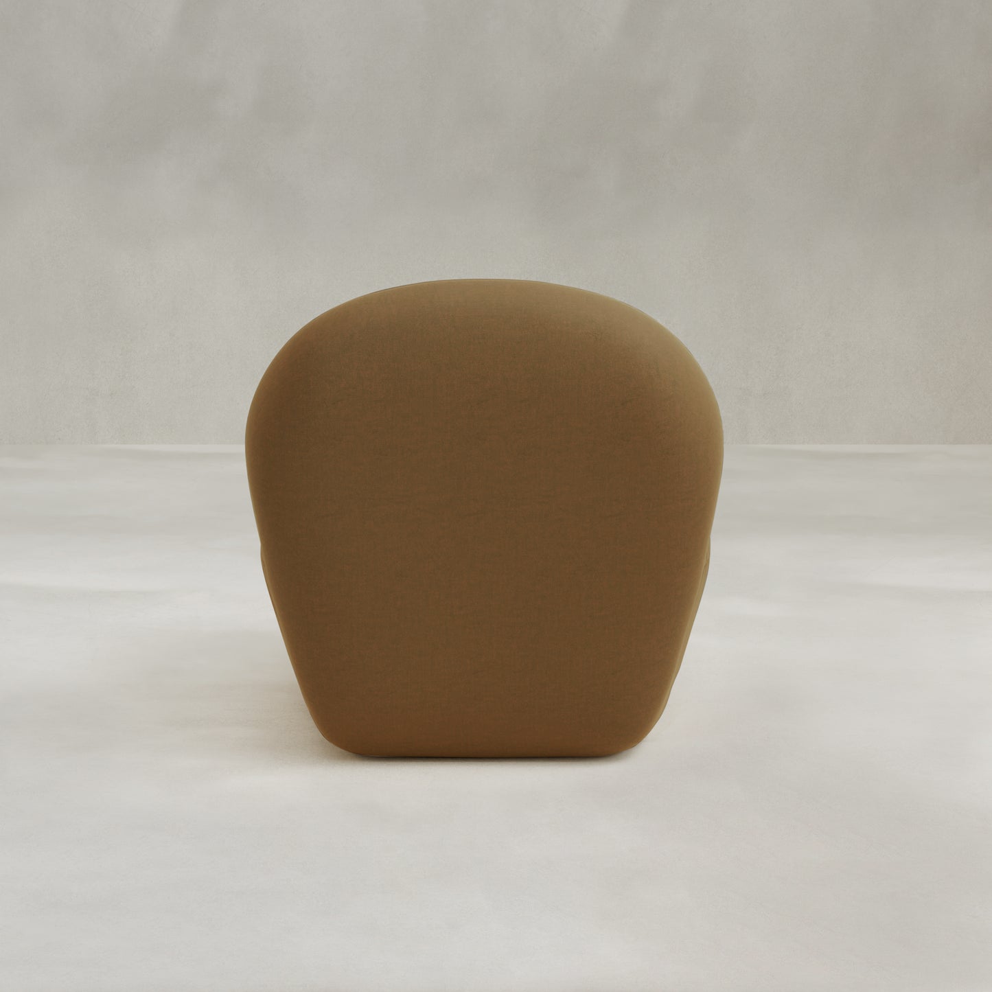 The Colette Chair is a modern, minimalist brown seat with a rounded backrest and sleek, hidden legs, featuring rich texture and set against a neutral, light background.