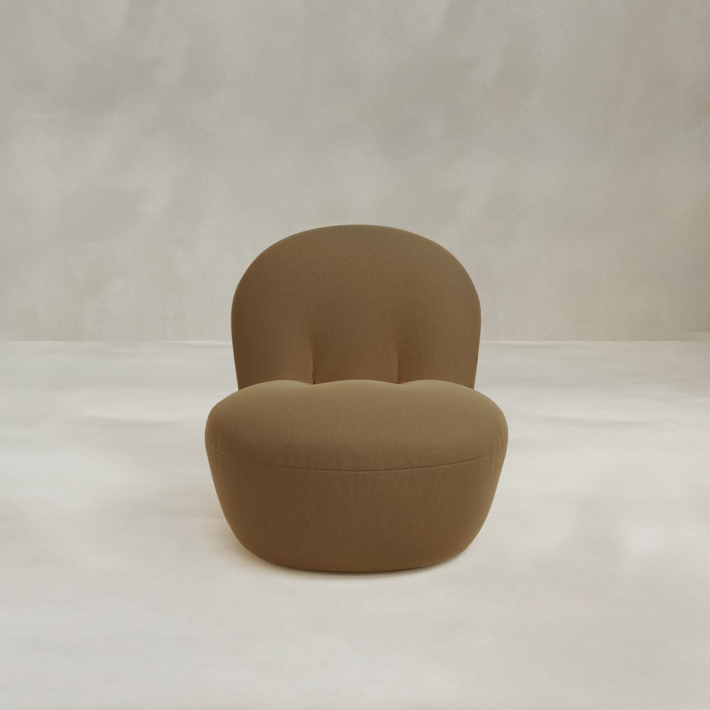 The Colette Chair, a modern brown upholstered lounge chair with a rounded backrest and seat, adds contemporary flair and rich texture to any space against a light, neutral backdrop.