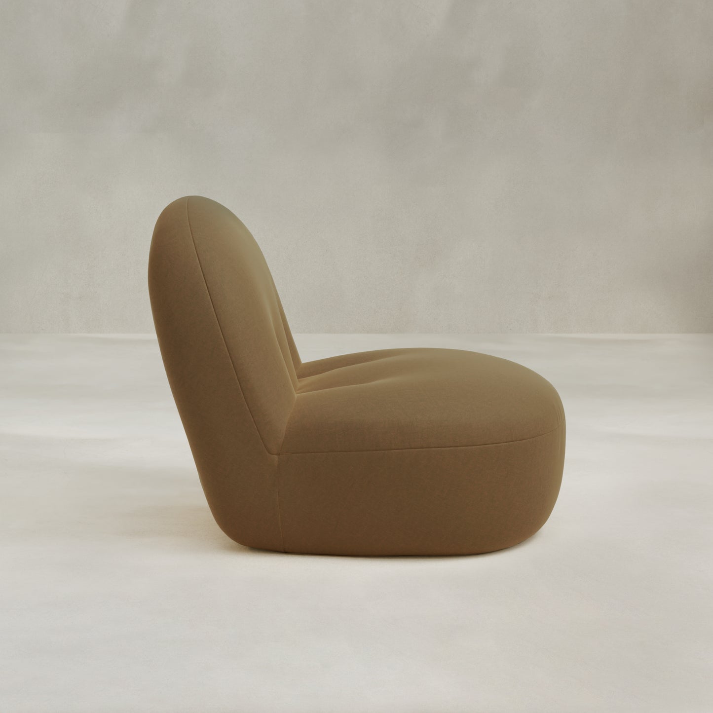 The Colette Chair, a modern minimalist lounge chair in brown with a rounded, low-profile design and rich texture, is displayed in side view against a plain light background.