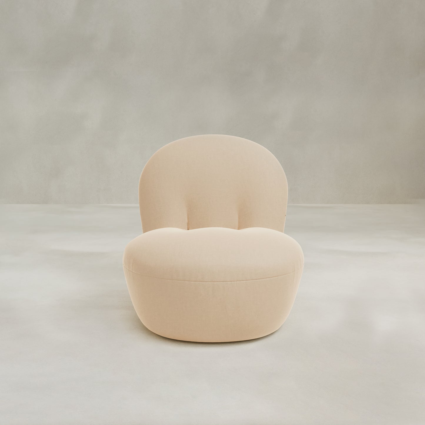 The Colette Chair is a modern beige upholstered accent chair with plush cushions, rounded edges, and a curved backrest, shown against a light gray background for contemporary flair.