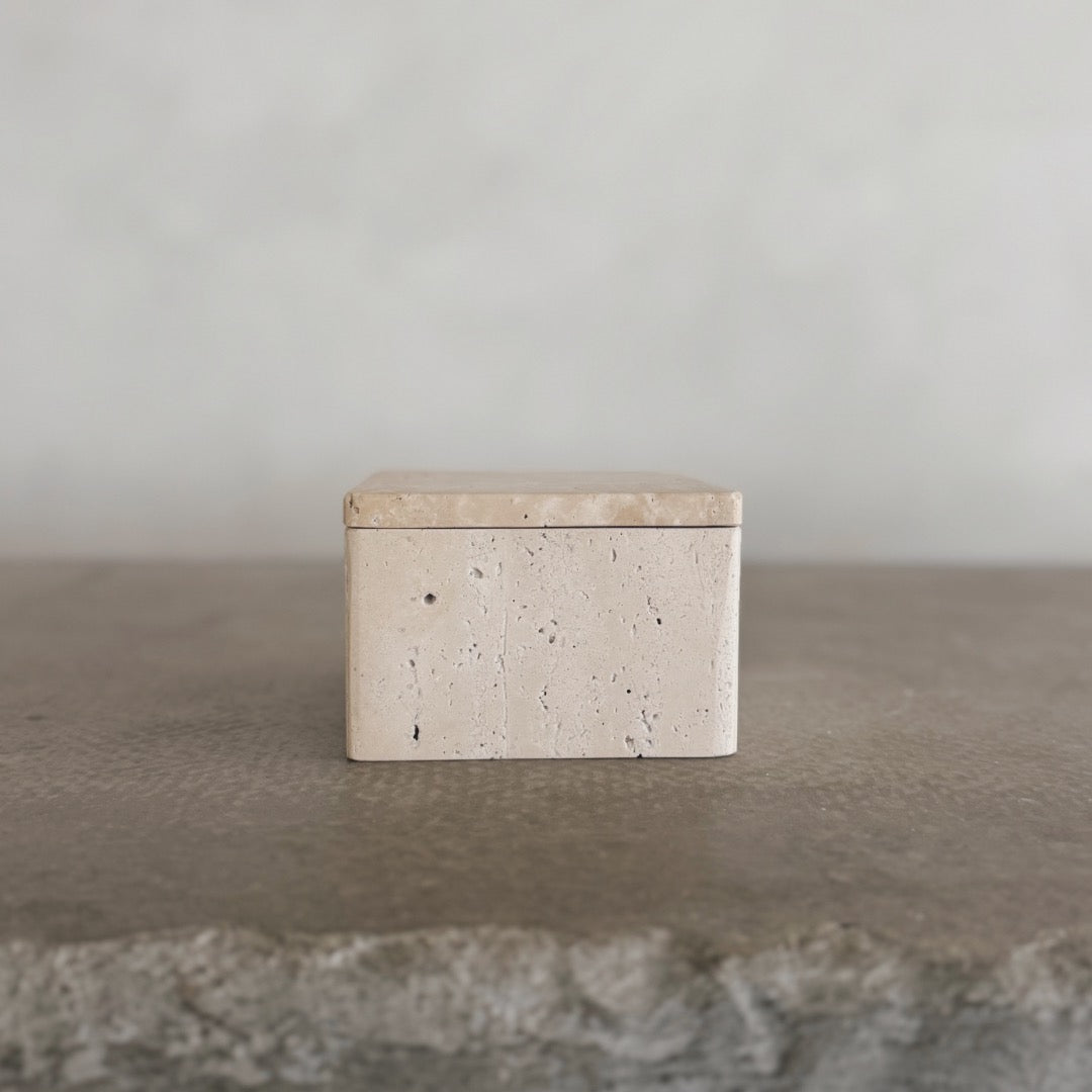The Celeste Vault with Lid, a small rectangular beige stone box, rests on a textured gray surface against a plain, light background.