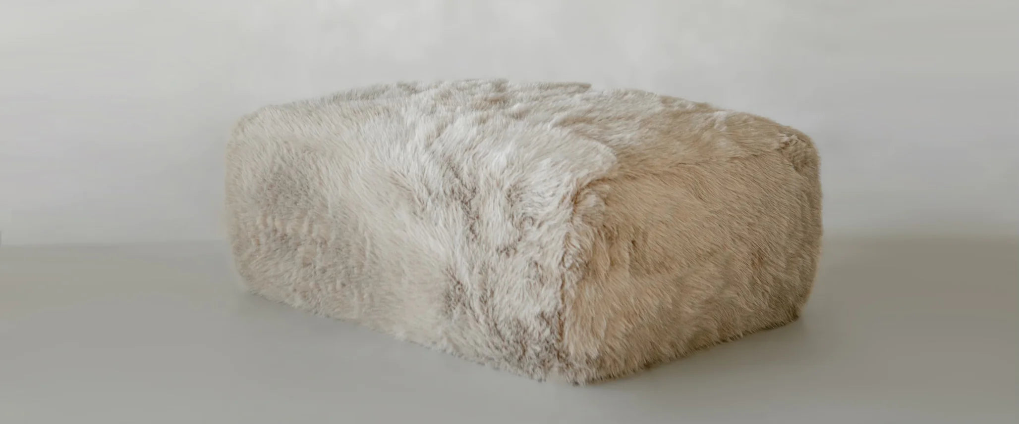 A large, rectangular Yeti Ottoman covered in plush faux fur rests on a smooth, light-colored floor against a plain, light background.