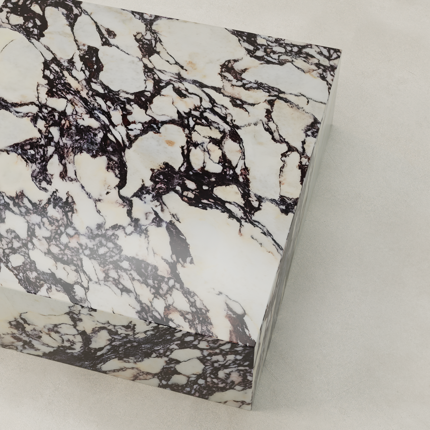 A close-up of the Calacatta Coffee Table XL showcases its rectangular marble top with a cream base and dark, intricate veining, ideal for adding sophistication to any space, set on a light, textured surface.