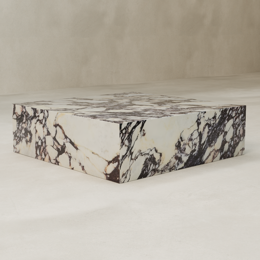 The Calacatta Coffee Table XL is a low, square table crafted from luxurious Calacatta Viola marble with striking black and brown veins, displayed on a light textured floor against a beige wall.