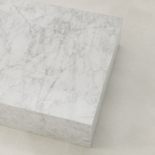 The Griselle Marble Coffee Table XL, featuring a large rectangular design with gray veining, sits on a pale, smooth surface and adds an elegant touch to the space.