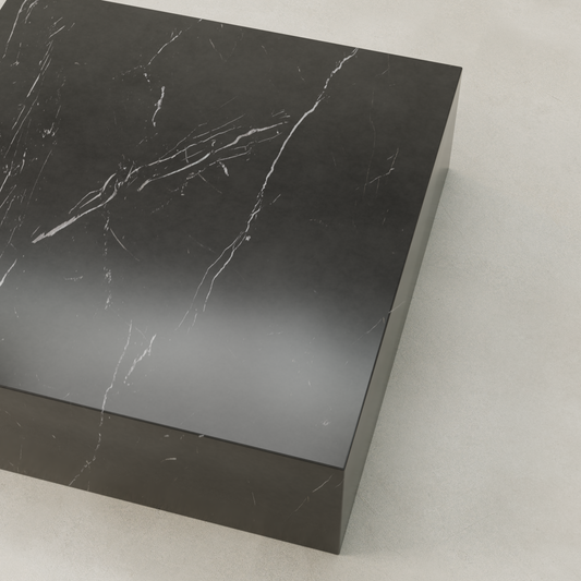 The Obscara Coffee Table XL, a rectangular black marble piece with white veining, is displayed on a light, textured surface and viewed from an angled top perspective.
