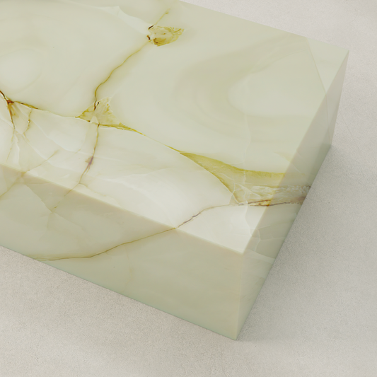 The Blanchaire Onyx Coffee Table features smooth, polished light green stone with natural beige and gold veining, displayed on a light-colored textured surface.