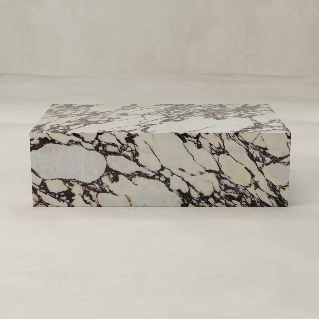 The Calacatta Coffee Table, featuring a polished Calacatta Viola marble top with a cream base and striking dark brown veining, brings refined elegance to any sophisticated space, especially against a light backdrop.