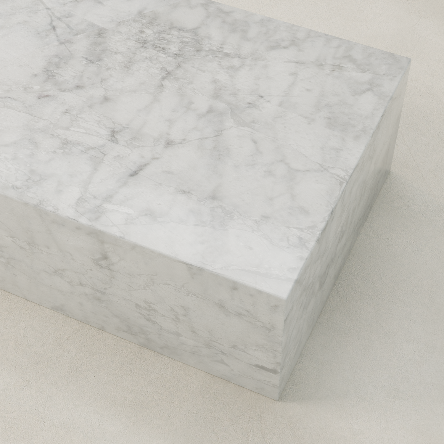 The Griselle Marble Coffee Table features a large rectangular block of smooth white marble with gray veining, resting on a light, textured surface for an elegant, minimalist look.