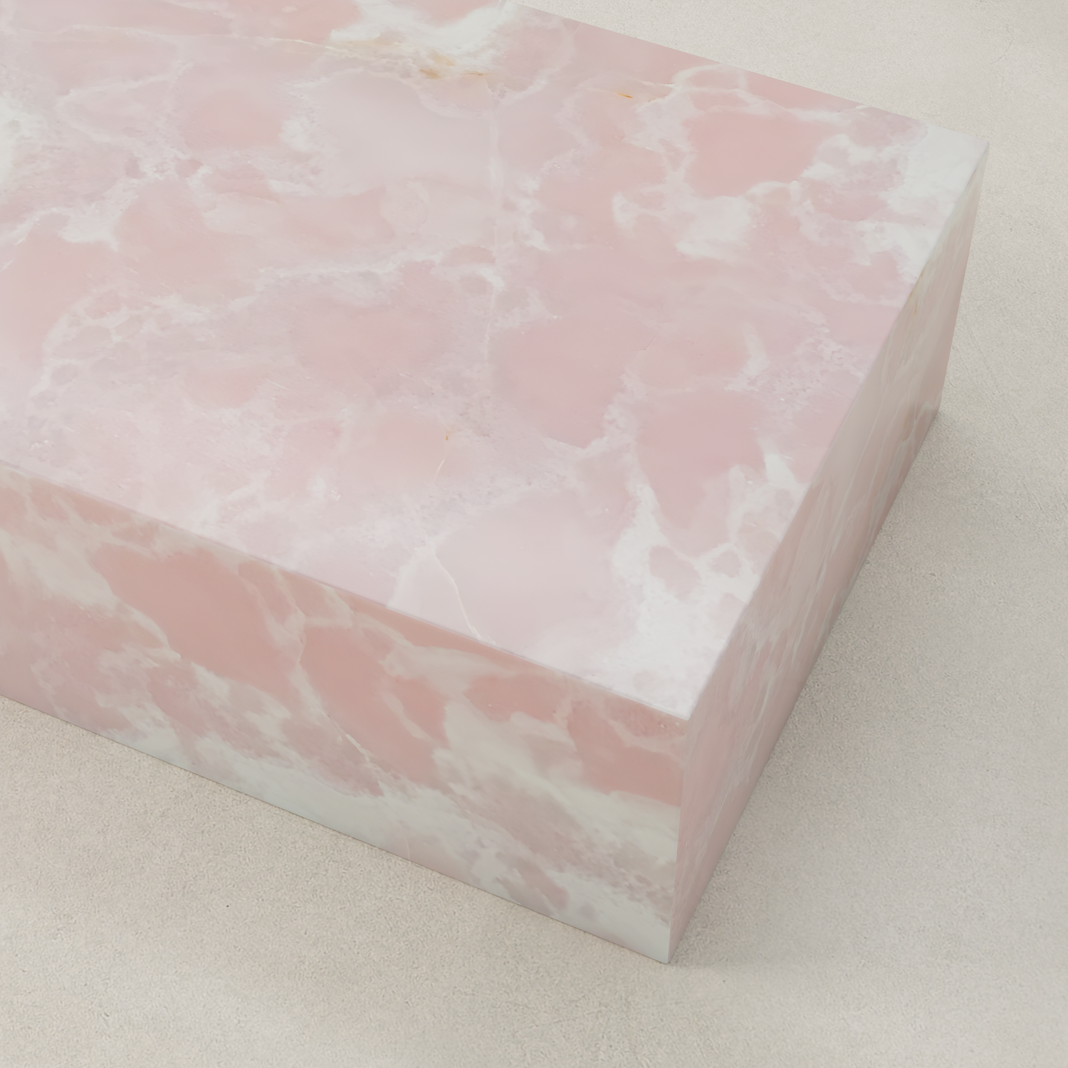 A rectangular block with a smooth surface shows a pink and white marbled pattern, resembling the Cora Onyx Coffee Table, and is placed on a light-colored background.