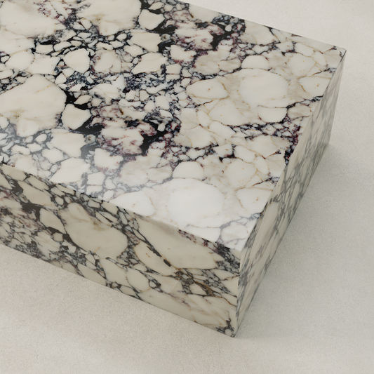 The Azurine Marble Coffee Table features polished marble with a white base and striking black and purple veining, resting on a smooth, light-colored surface to highlight its modern design.