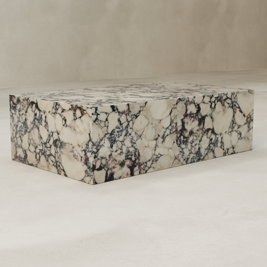 The Azurine Marble Coffee Table, featuring a modern rectangular design and striking cream and black veining, sits on a smooth, light-colored floor against a neutral background.
