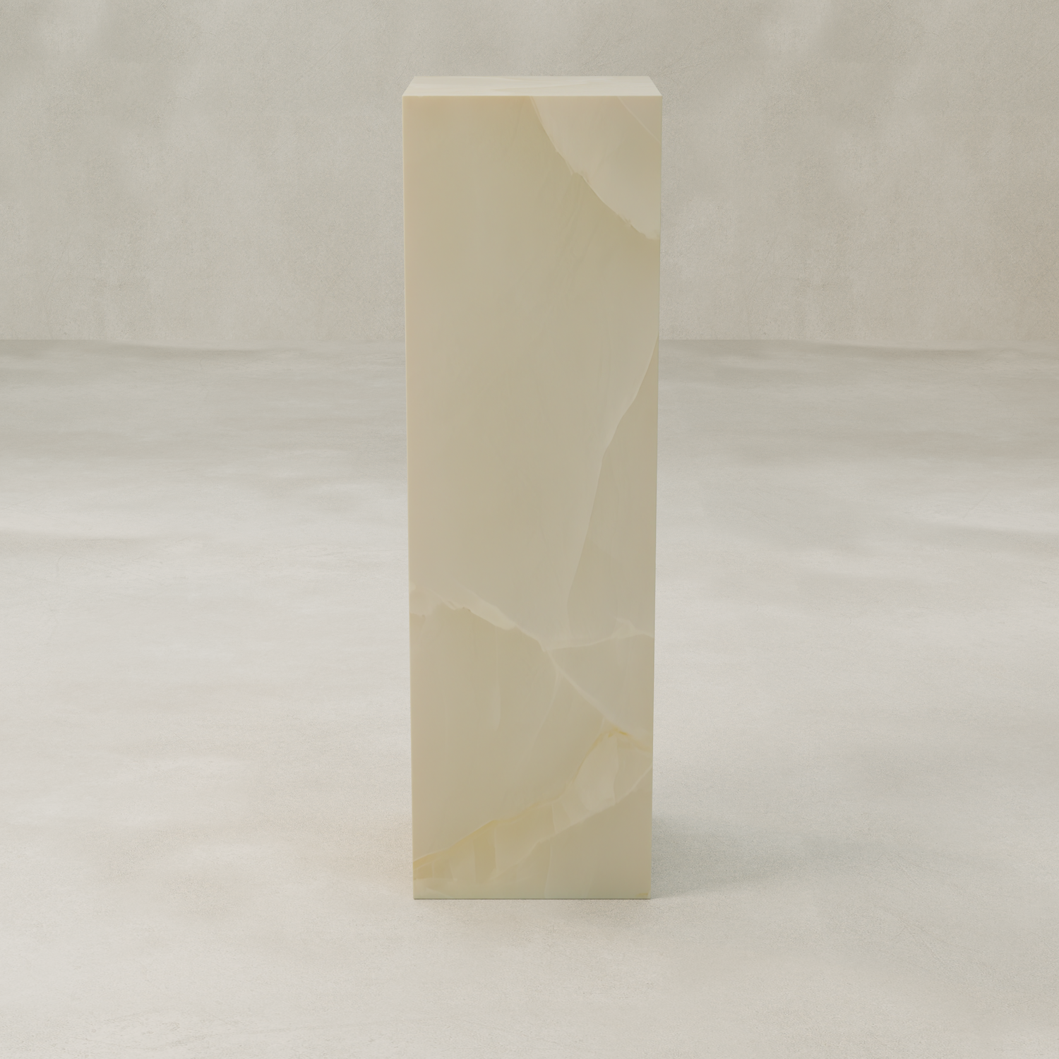 The Lunelle Onyx Tall Tower Plinth features smooth, cream-toned stone with a milky hue and subtle golden veining, standing tall and rectangular on a light, textured surface against a neutral backdrop.