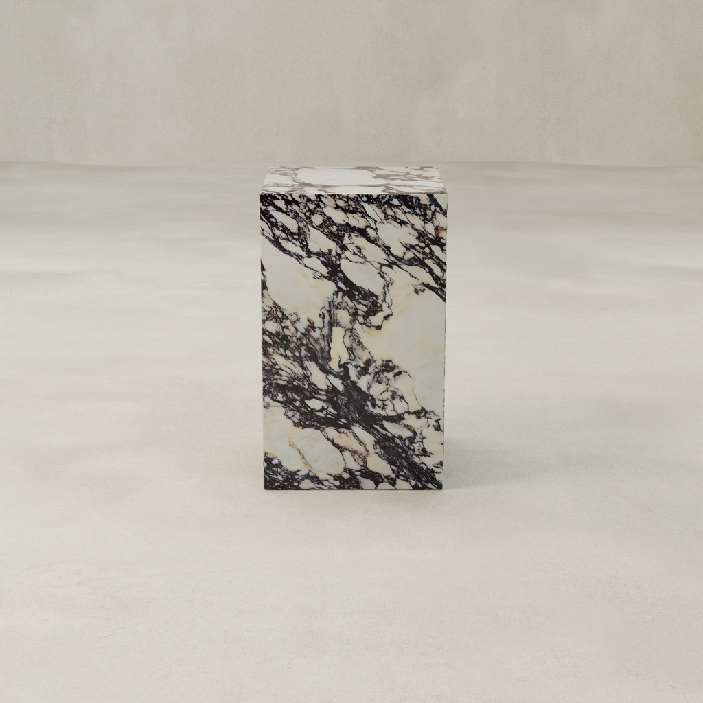 The Calacatta Tall Plinth, featuring luxurious black and white veining, stands on a smooth, light-colored floor against a plain beige background.