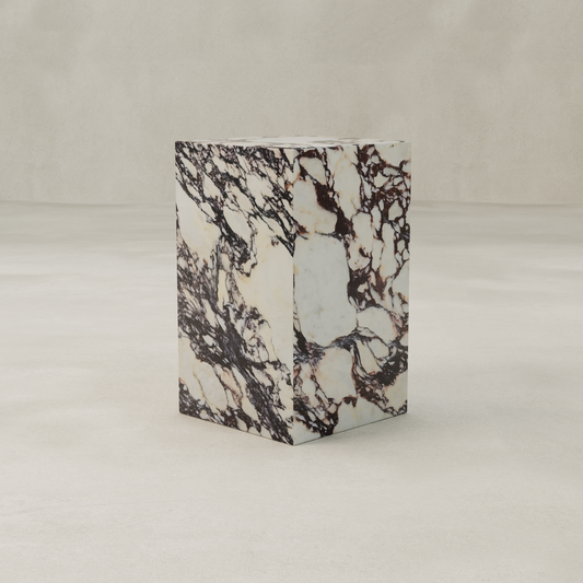 The Calacatta Tall Plinth, featuring a cream-toned surface with elegant Calacatta-style veining, stands on a smooth light beige floor against a matching plain backdrop.