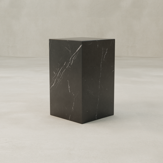The Obscara Plinth - Tall is a sleek, rectangular black marble stand with bold white veining, showcased on a smooth beige surface and neutral background for an elegant architectural accent.