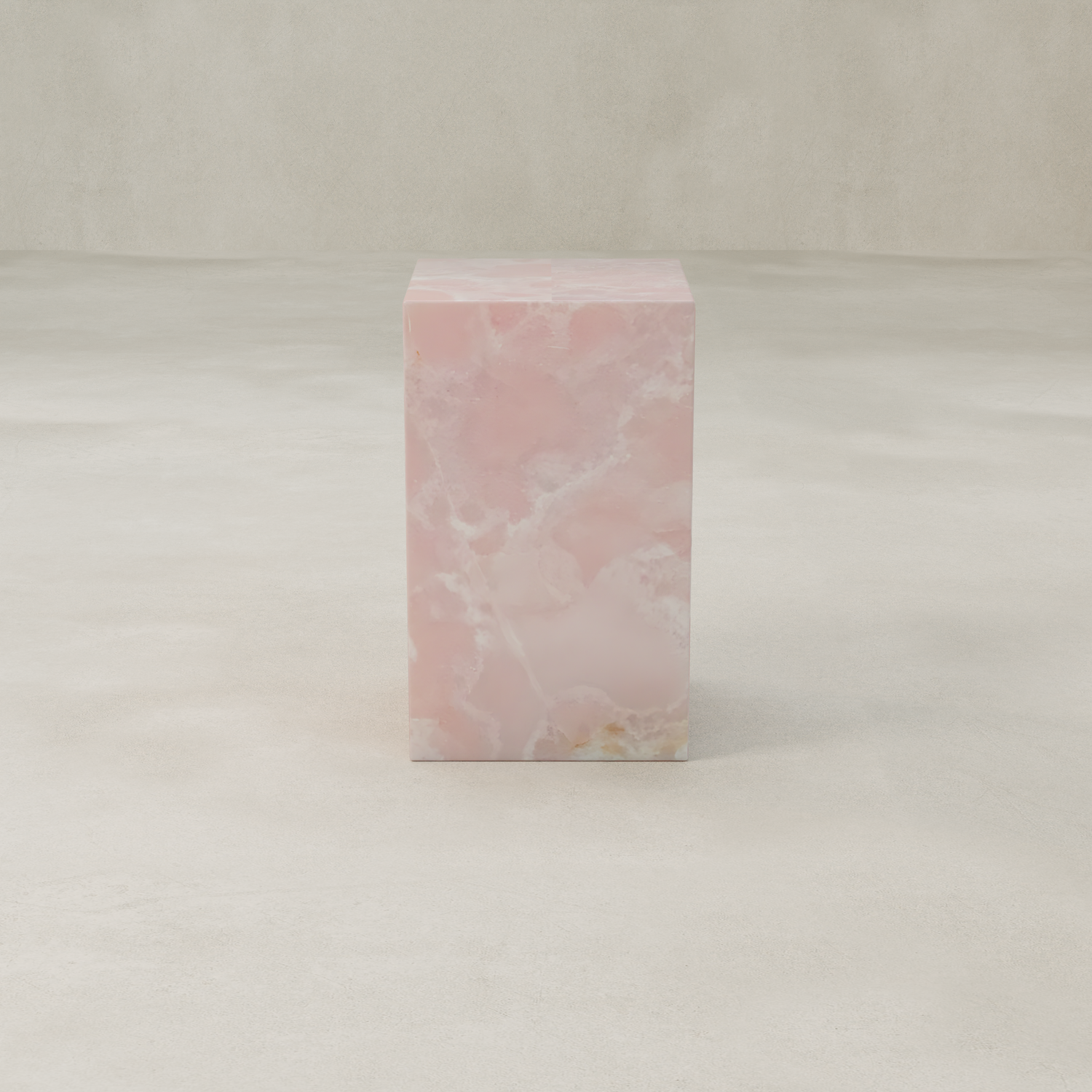 The Cora Tall Plinth, made from pink onyx with cloudy white and light brown veining, stands rectangular on a smooth, light floor against a beige background.