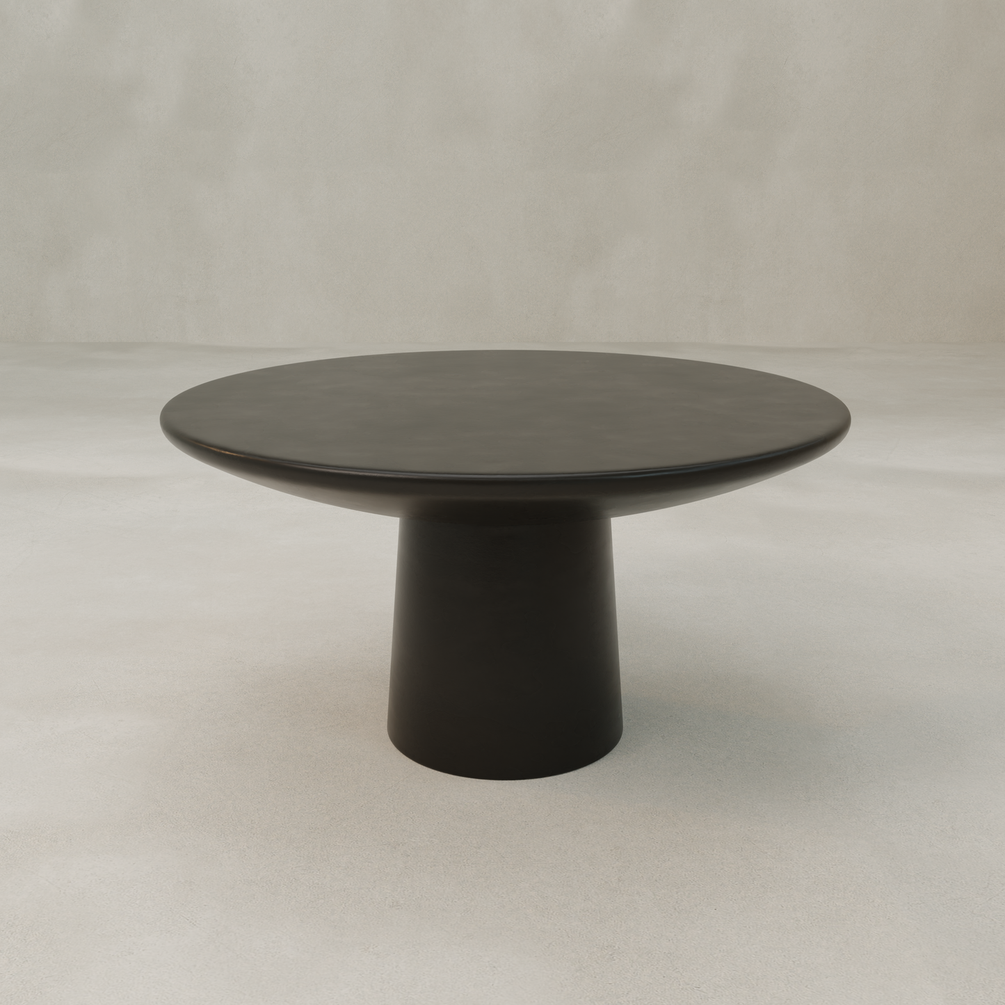 The Arrio Table is a modern, minimalist round table featuring a thick, broad base and cylindrical pedestal, shown in a neutral, light-colored room with a plain background.
