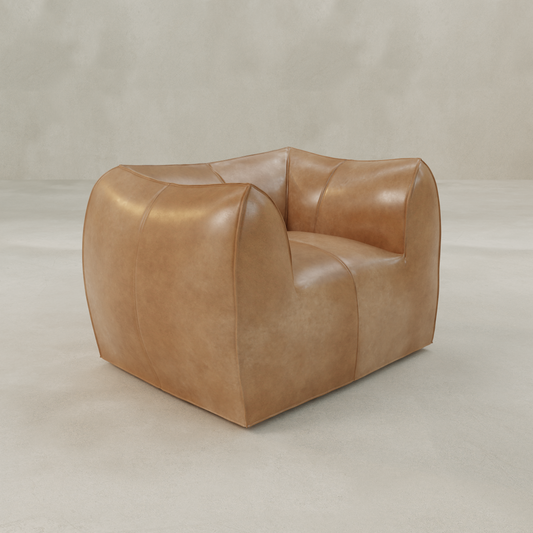 The Bambon Armchair, featuring a modern square shape with soft, rounded edges and vintage leather upholstery, stands on a smooth neutral floor against a plain background.