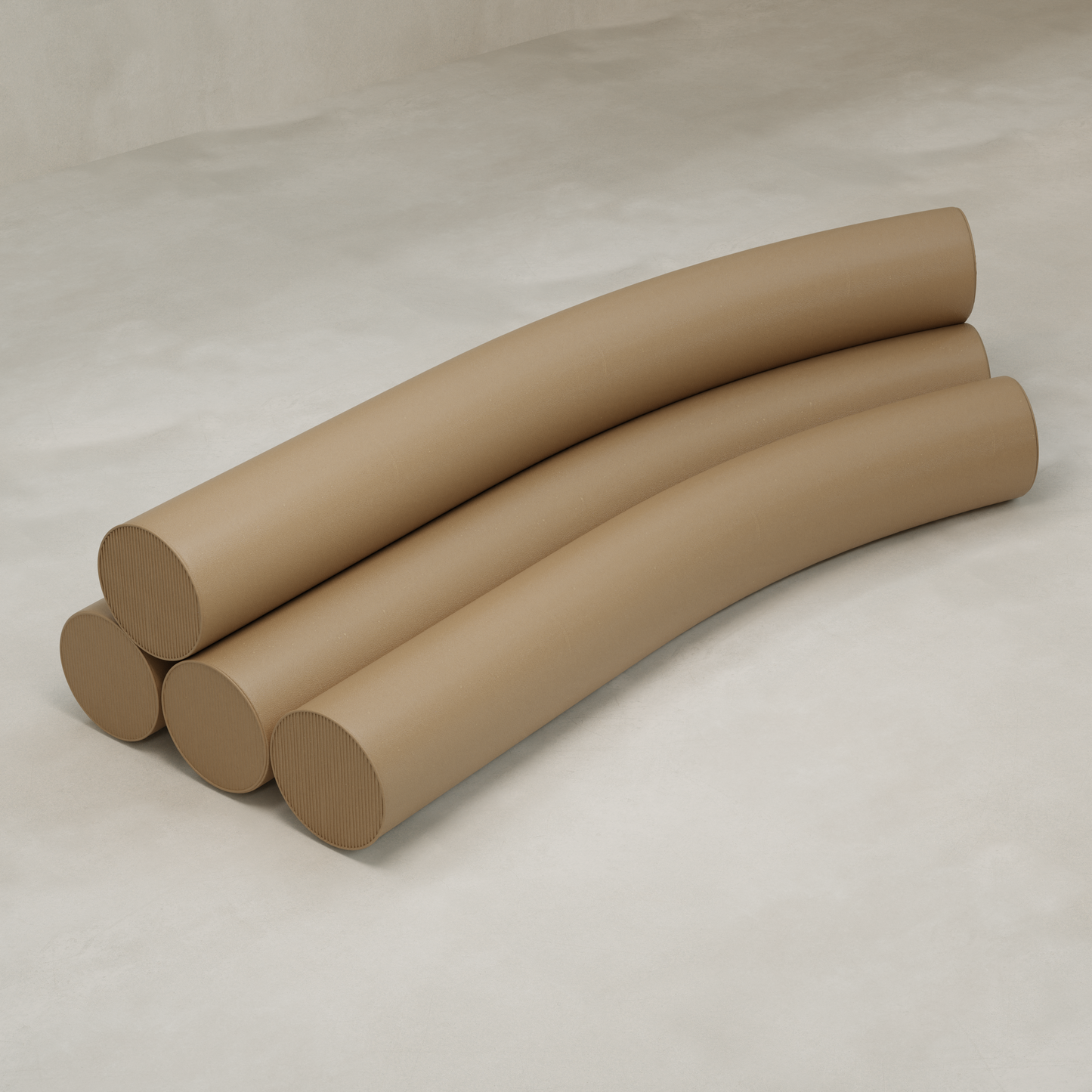 Four large, curved, cylindrical tubes are stacked parallel on a smooth, light floor against a plain background, forming the playful and modern shape of the Cylindra Sofa.