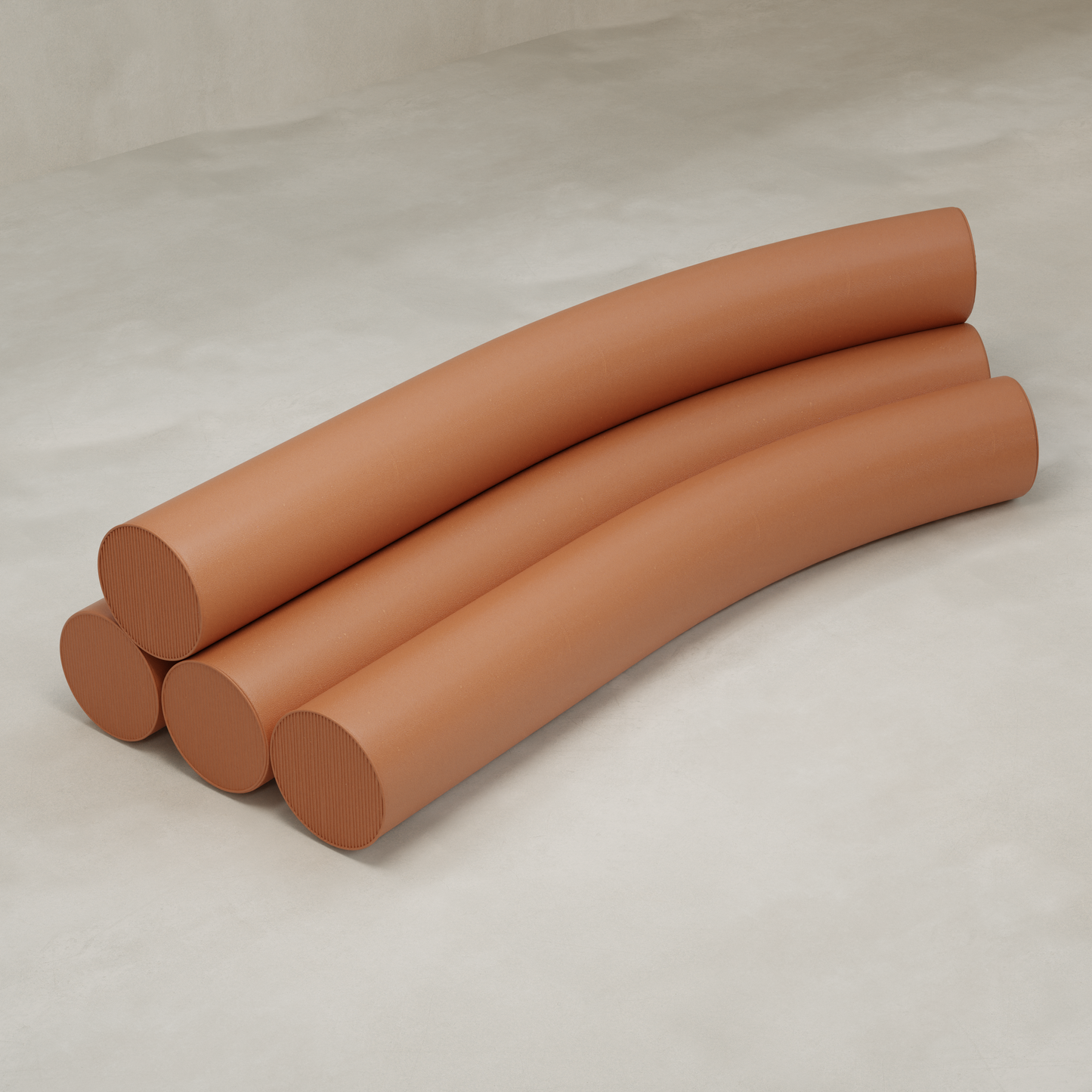 Four large, curved, terracotta Cylindra Sofa sections are stacked on a smooth, light beige surface in neat parallel formation, evoking neotenic minimalism.
