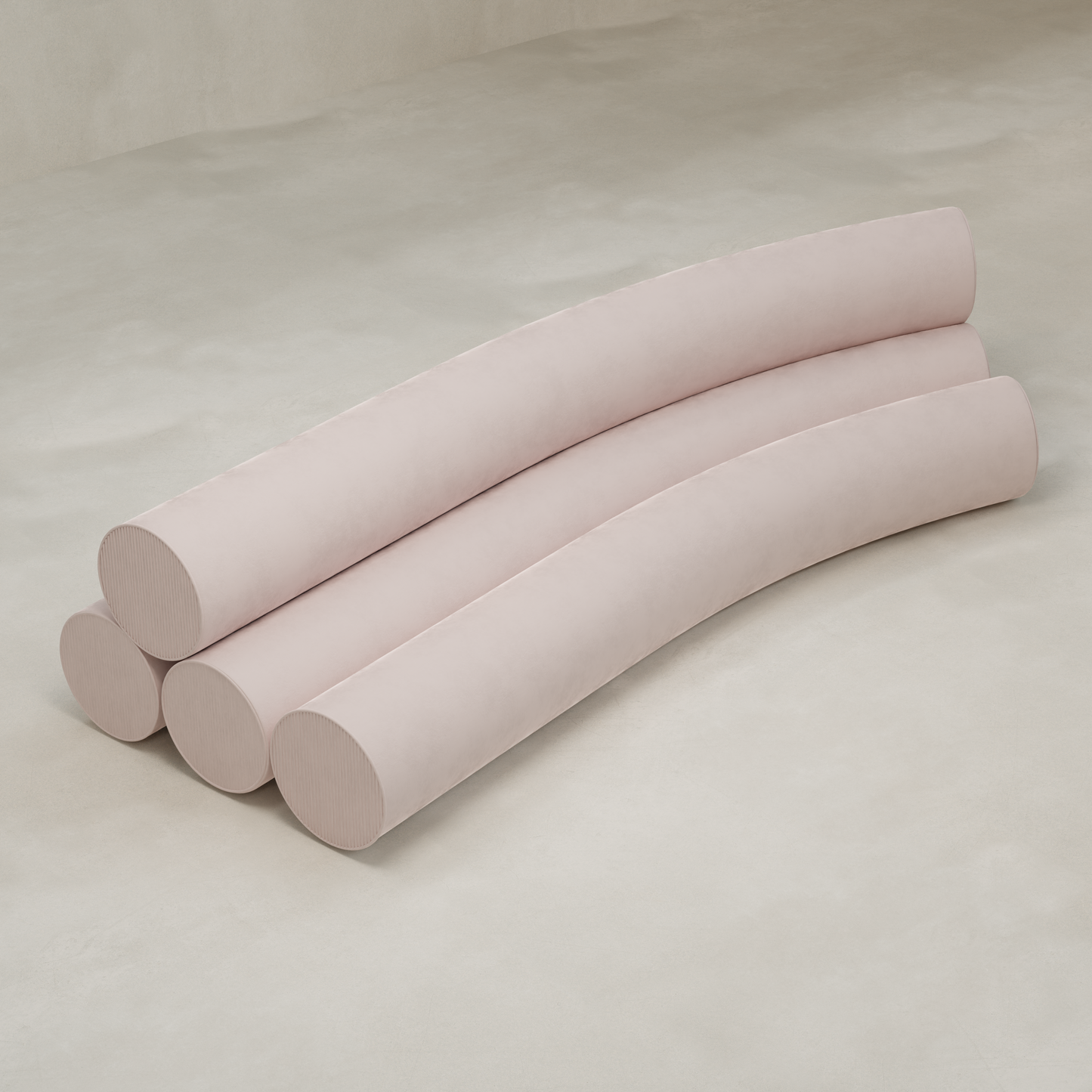 Four long, cylindrical, light pink cushions are arranged parallel on a smooth beige surface, evoking the playful shapes of the Cylindra Sofa—a modern neotenic design ideal for minimalist, contemporary spaces.