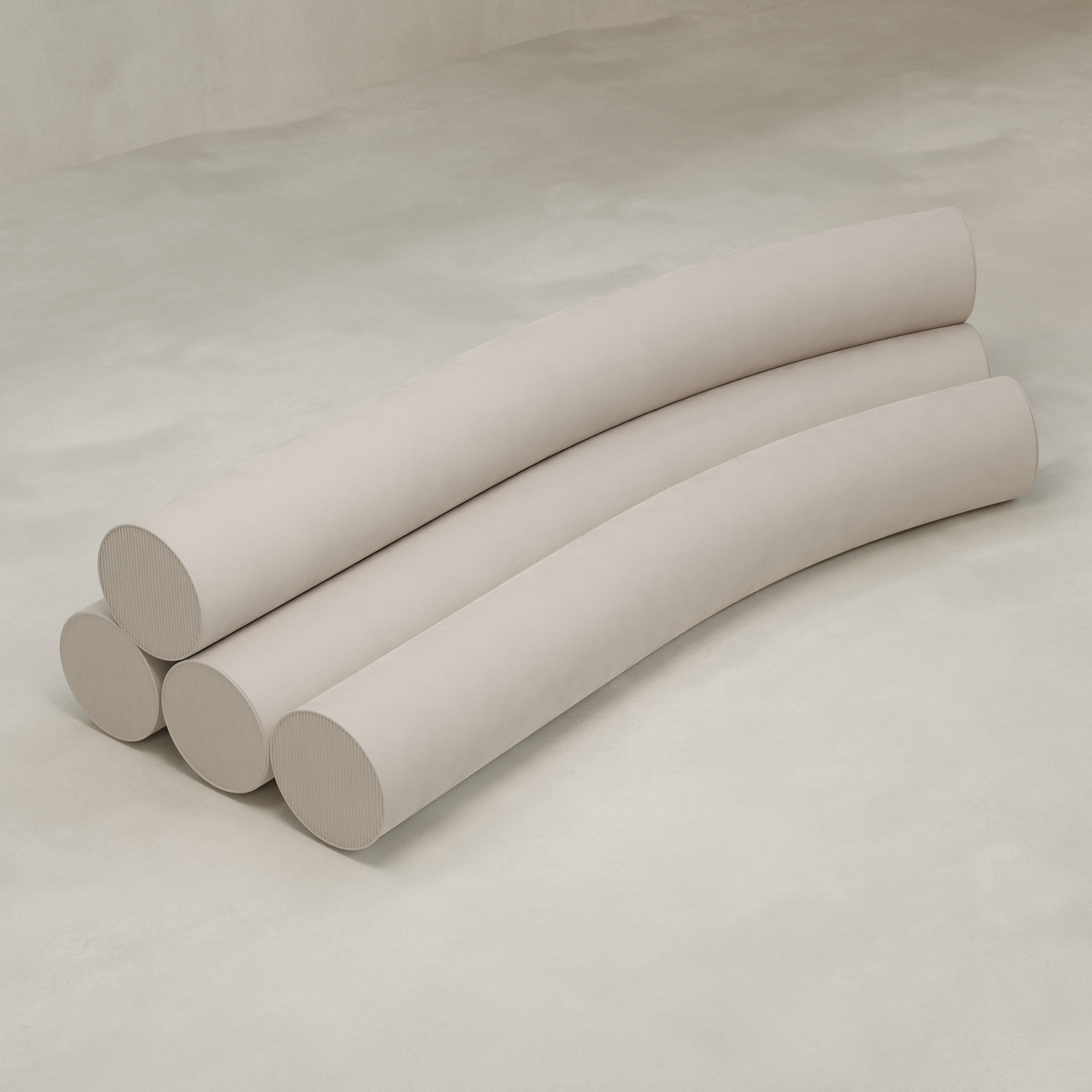 Four large, light beige cylindrical cushions, part of the Cylindra Sofa, are stacked in a staggered wave-like arrangement on a smooth neutral floor, evoking playful neotenic forms.