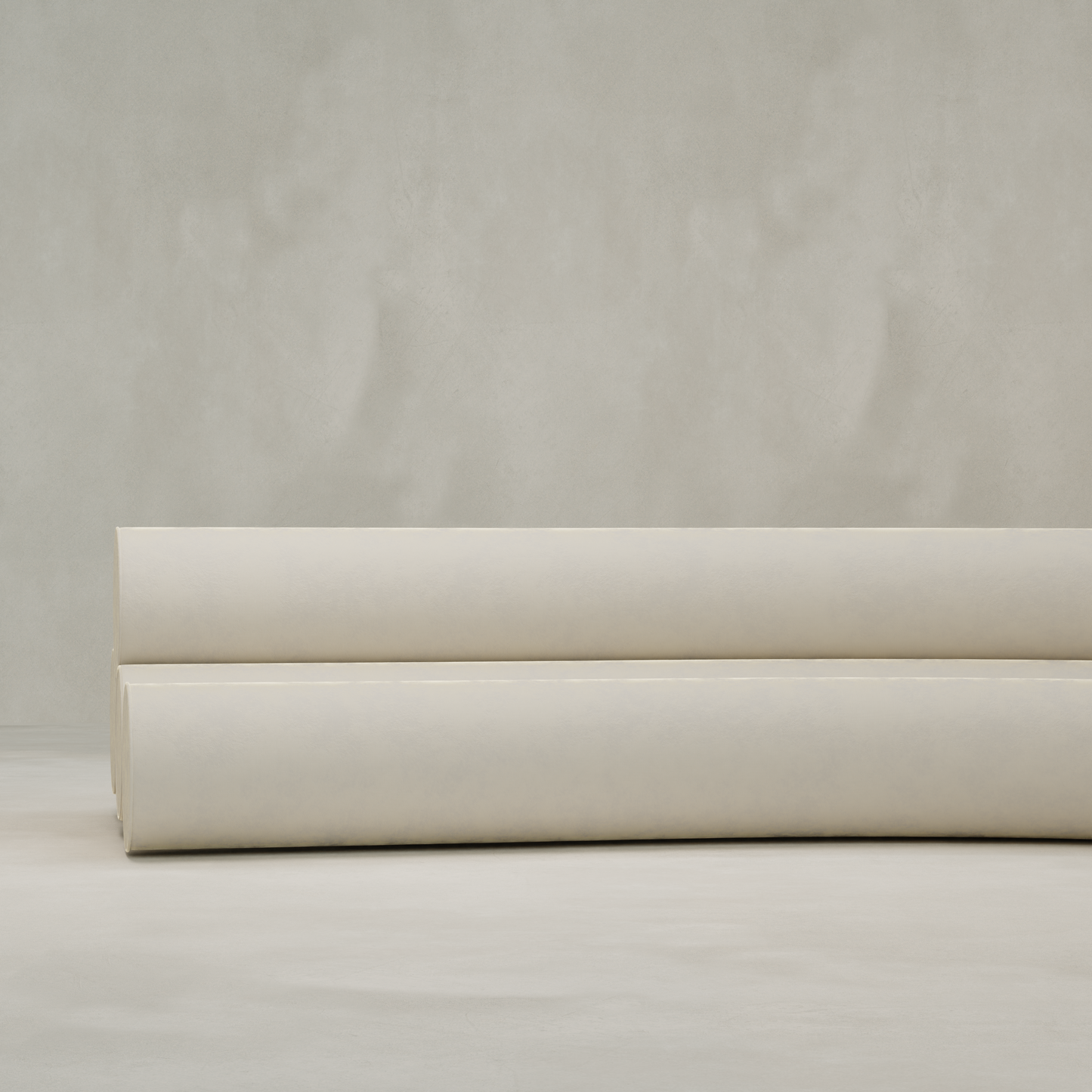 Two large rolls of light beige fabric rest on a neutral surface—perfect for upholstering a Cylindra Sofa—set against a plain, textured background.