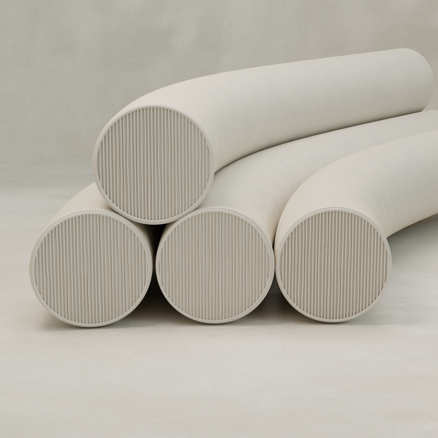 Four large, pale cylindrical forms with ribbed ends—three as the base and one curved on top—are stacked on a smooth surface against a plain background, showcasing the modern Cylindra Sofa’s distinctive neotenic-inspired design.