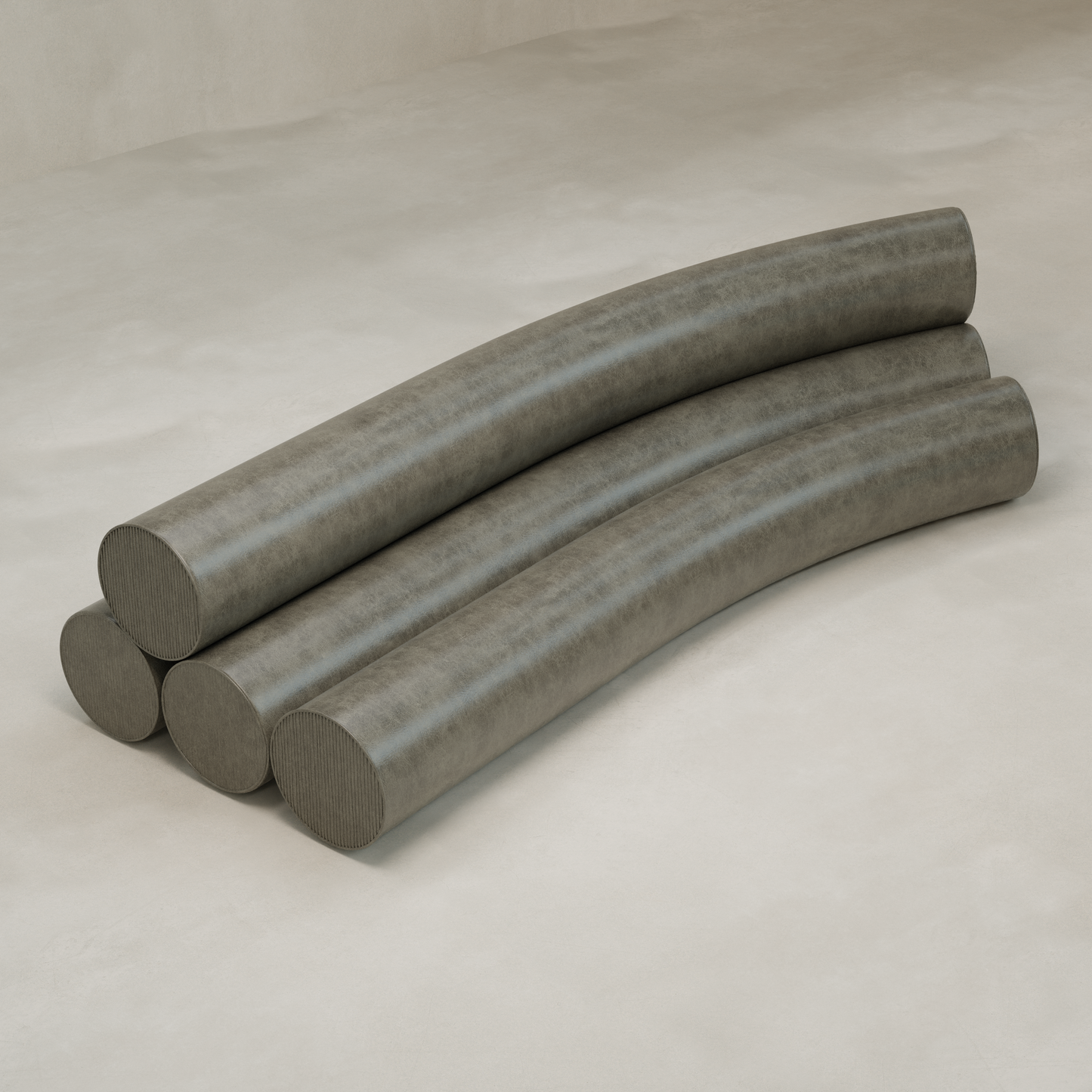 Four large, curved, gray cylinders are stacked in two layers on a light surface to form the Cylindra Sofa, with each cylinder slightly curved and parallel, creating a playful neotenic-inspired design.