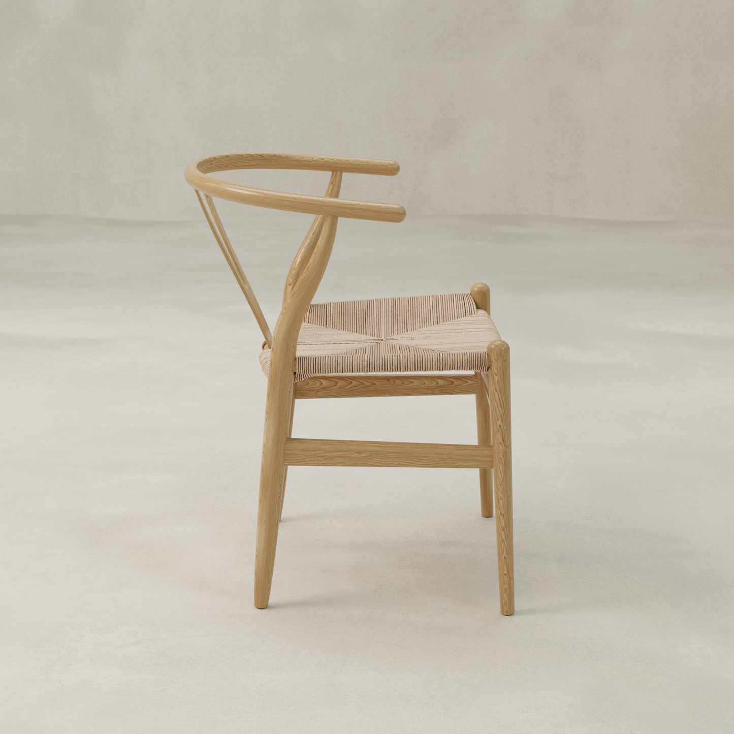 The Elsa Chair is a minimalist Y-back dining chair with a curved backrest and woven seat, displayed from the side against a light neutral background.