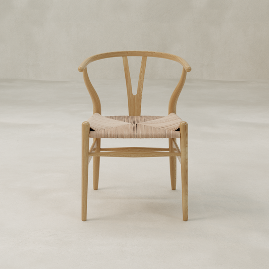 The Elsa Chair features a wooden Y-back, curved backrest, and woven seat. Its minimalist Scandinavian design suits any light, neutral space—ideal as a dining room chair for gatherings around a farmhouse table.