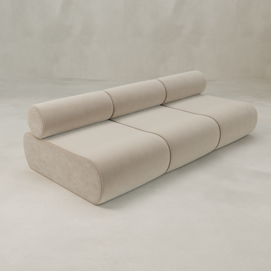 The Nuage Three Seater Modular Sofa features a modern, minimalist beige design with rounded edges, three seat sections, and a cylindrical backrest, shown against a plain light background.