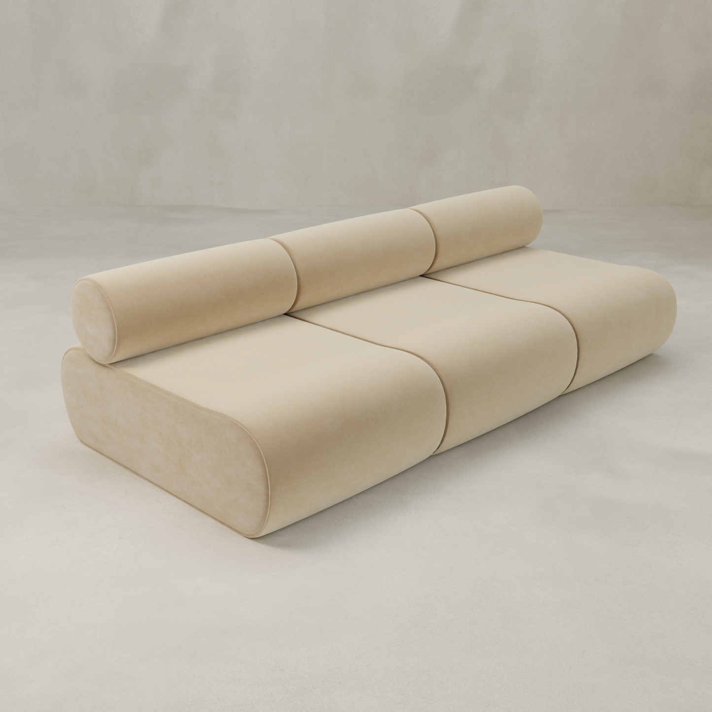 The Nuage Three Seater Modular Sofa in beige velvet features a modern, minimalist design with a cylindrical backrest and rounded edges, displayed against a light, neutral background.