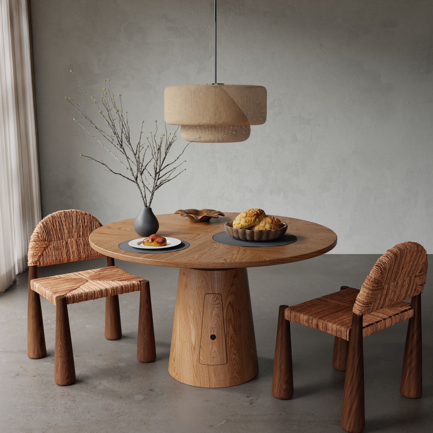 The Nola + 2 Bardo Dining Set features a round wood table with two woven chairs, complemented by a gray vase with branches, plate of pastries, and pendant lamp in a minimalist room with gray walls and floor.