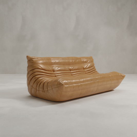 The Rolo Lounge Three Seater, a modern tan leather sofa with a low profile, deep seat, and ruched upholstery, adds subtle mid-century flair against a light gray background.