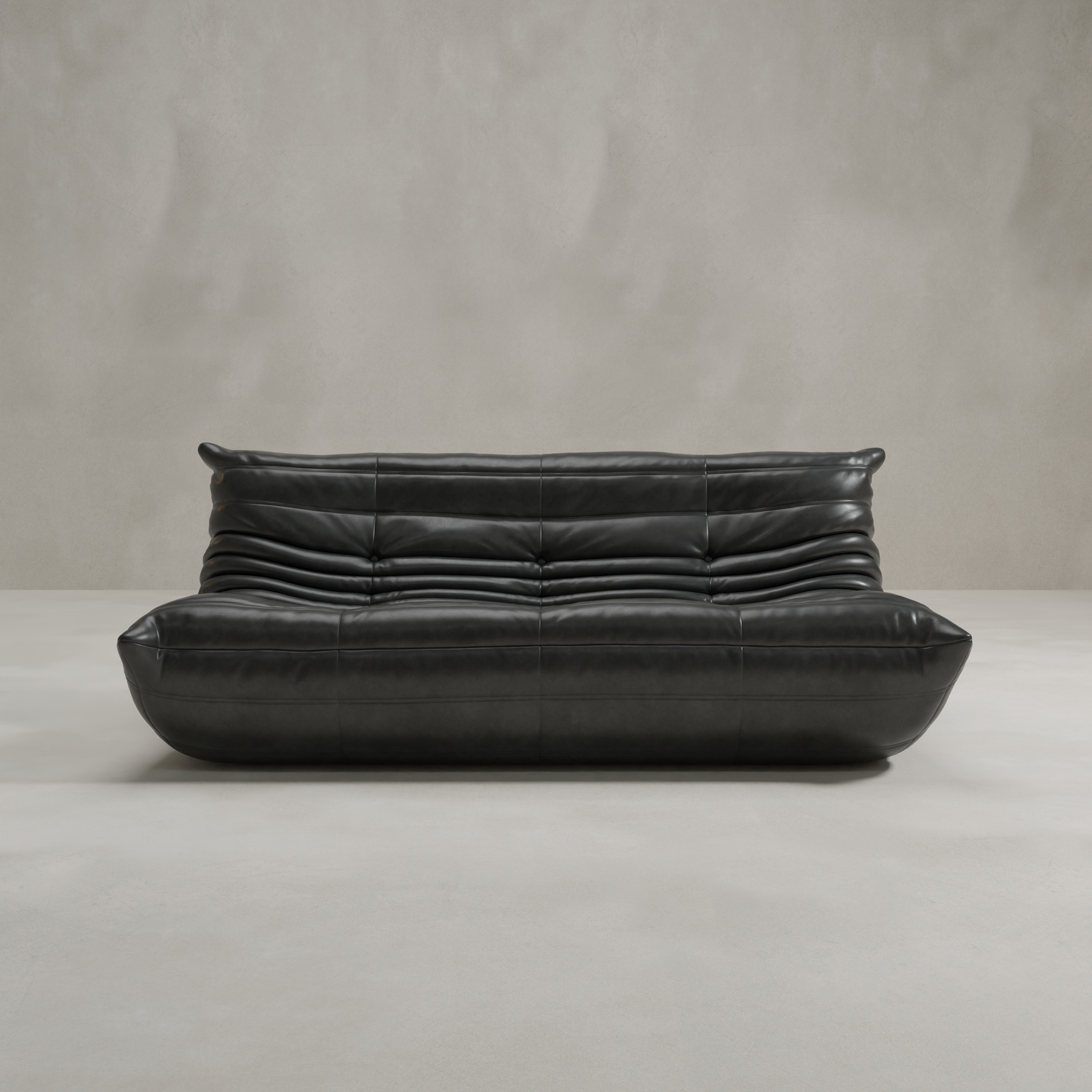 The Rolo Lounge Three Seater is a modern black leather sofa with deep horizontal tufting and a low, rounded design, evoking mid-century style as it rests on a light gray floor against a smooth beige wall.