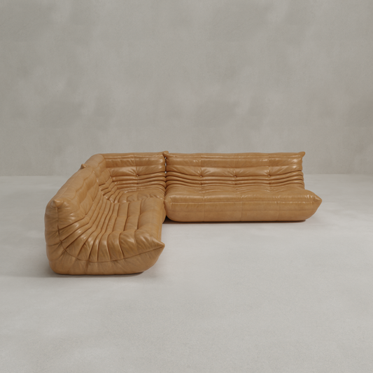 The Rolo Lounge Three Piece Sofa features a tan leather, tufted, low-profile design, set on a light grey floor against a plain wall, capturing the sleek aesthetic of mid-century style.