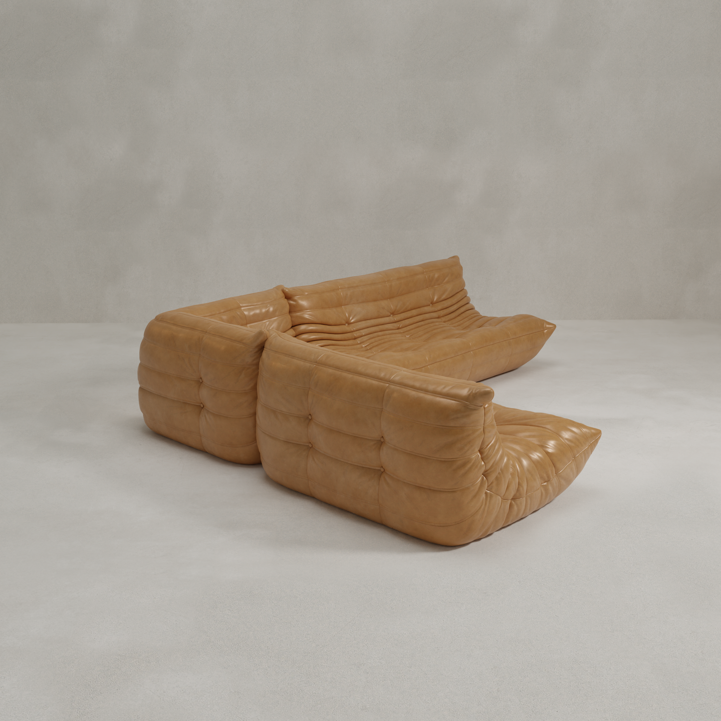 The Rolo Lounge Three Piece Sofa features modular tan leather, tufted and cushioned sections in an L-shape, set against a plain light gray background—ideal for pairing with a 70s inspired lounge chair.