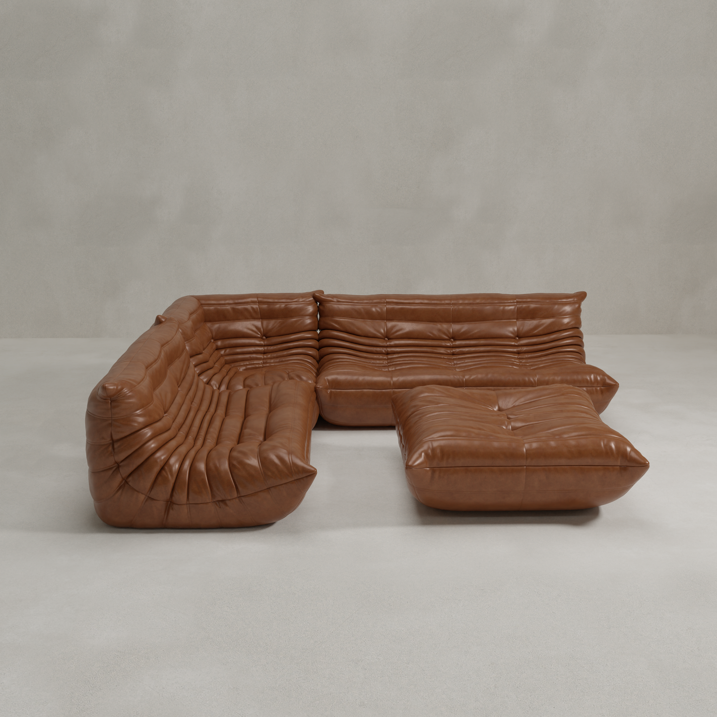 The Rolo Lounge Four Piece Sofa, a modular brown leather sectional with deep, plush cushions and a low-profile L-shape plus ottoman, highlights its flexible system and subtle mid-century style against a light floor and textured wall.
