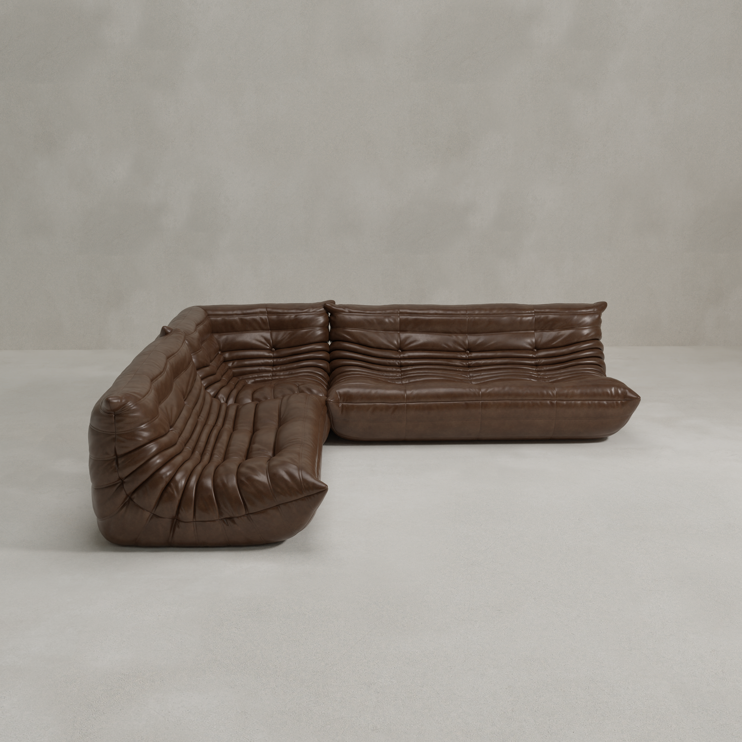 The Rolo Lounge Three Piece Sofa is a brown, tufted leather sectional with low back and deep seats in a mid-century L-shape, set on a light gray floor beside a textured gray wall.