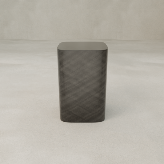 The Solaris Side Table Square, featuring a sleek dark sculptural design with rounded edges, stands on a smooth light surface against a plain neutral background.