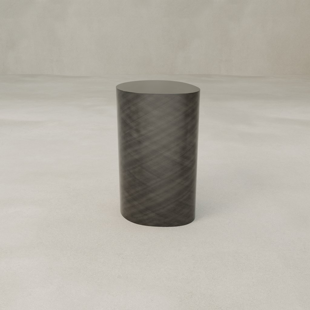 The Solaris Side Table Organic, a cylindrical dark luxury iron piece with a subtle diagonal pattern, stands on a light textured surface against a plain neutral background.