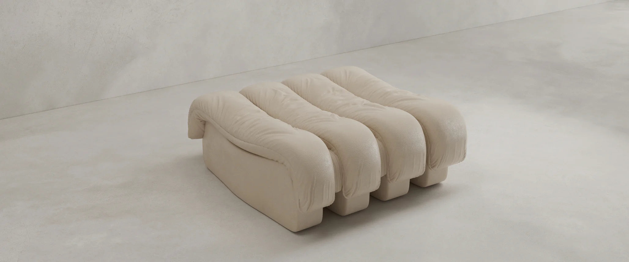 The Serpenti Sofa Ottoman is a modern, minimalist beige bench with three plush cushions and a textured finish, designed to seamlessly complement any modular setup, shown here against a plain light background.