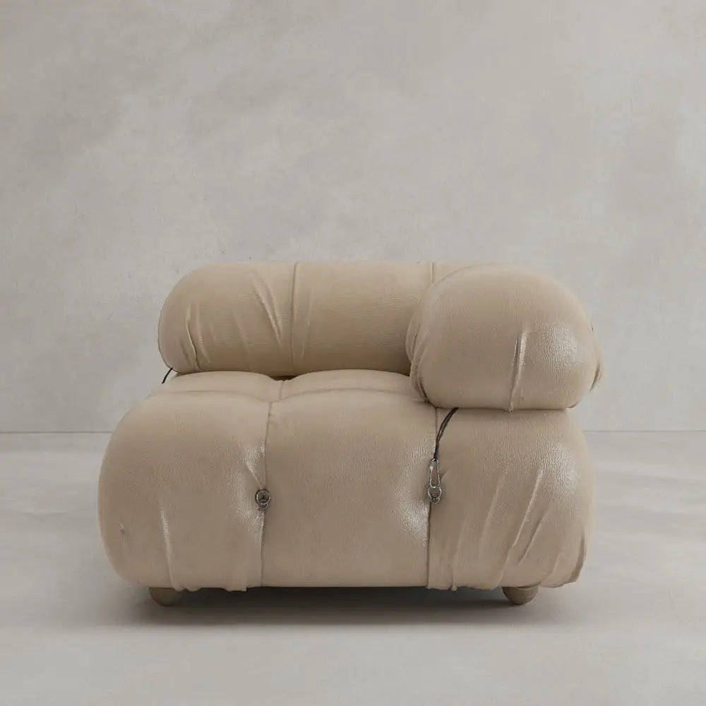 The Belmont Sofa Left Armrest features a modern, beige, plush design with rounded tufted details and visible metal fasteners, set against a light minimalist background—perfect for versatile, modular living spaces.
