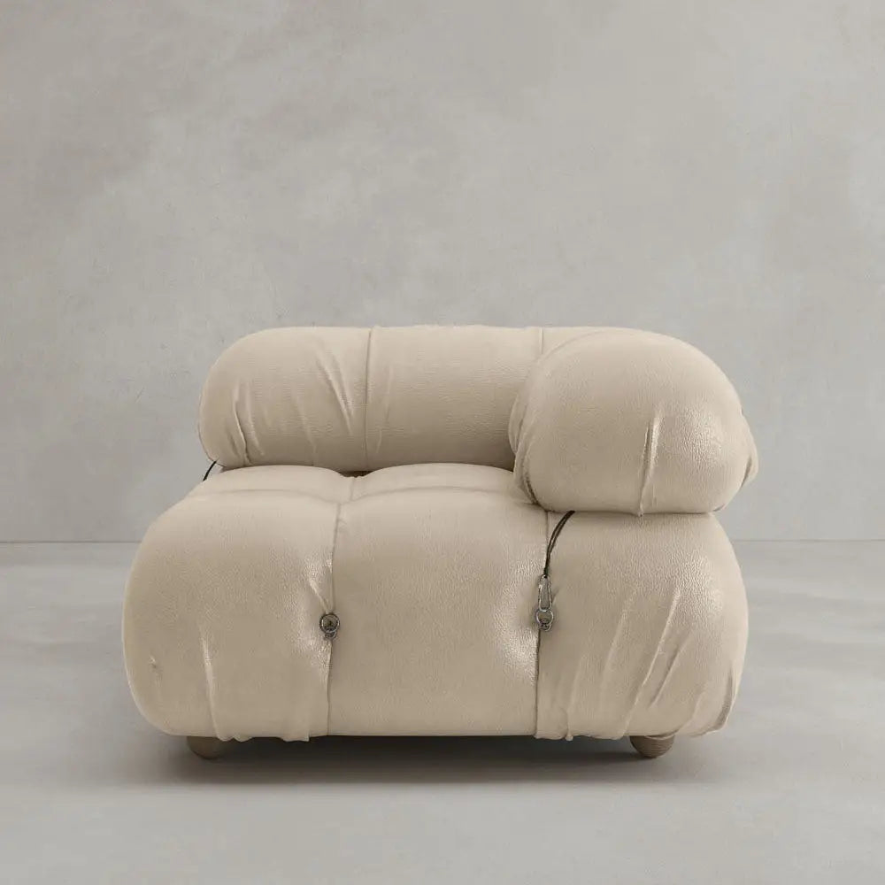 The Belmont Sofa Left Armrest features plush beige upholstery, rounded overstuffed cushions, marshmallow-like curves, and visible metal fasteners, set against a plain light gray background.