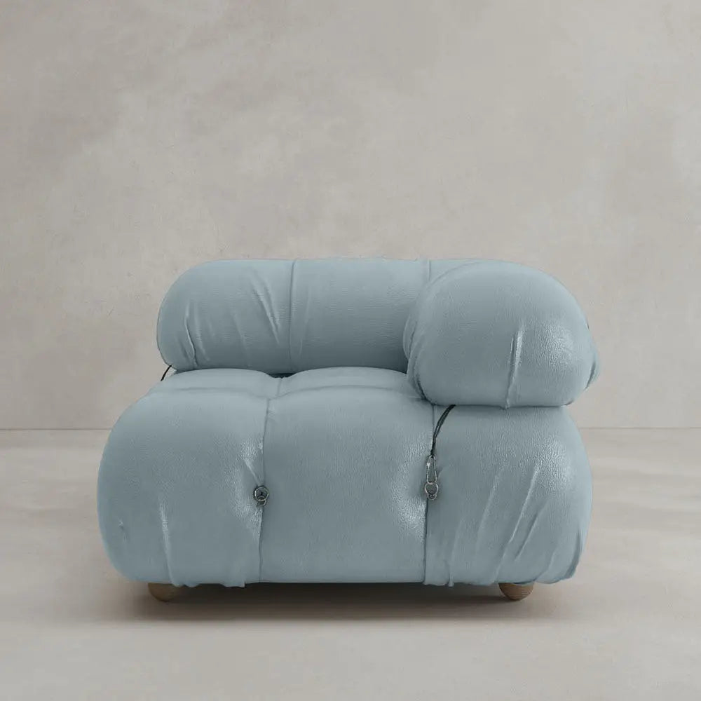 The Belmont Sofa Left Armrest is a modern, plush piece upholstered in soft light blue fabric with marshmallow-like curves, tufted design, and rounded edges, shown against a plain beige background.