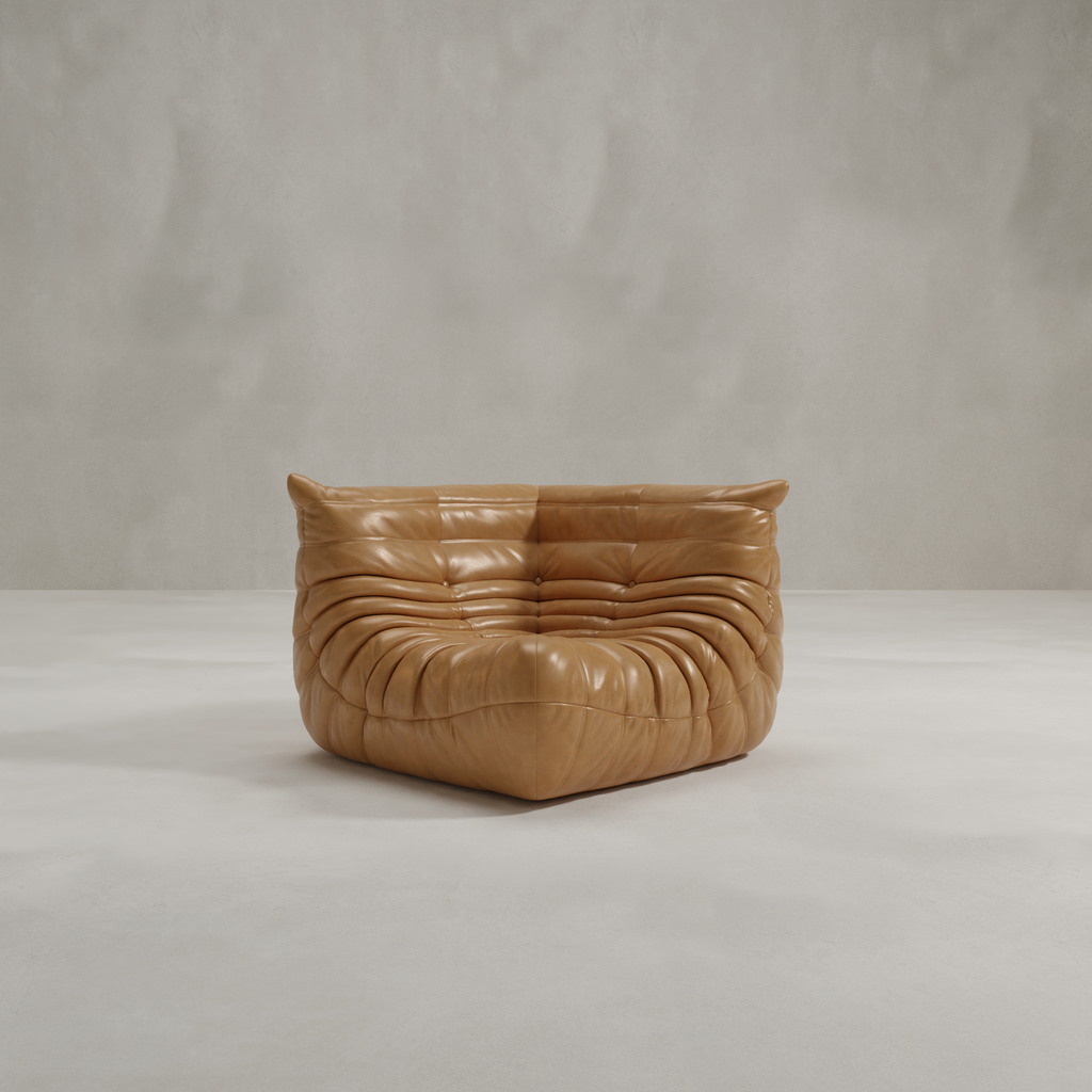 The Rolo Lounge Corner Sofa, with its tan leather, deep tufted cushions, and armless modular design, sits on a light floor against a plain gray wall—ideal for adding mid-century style to any space.