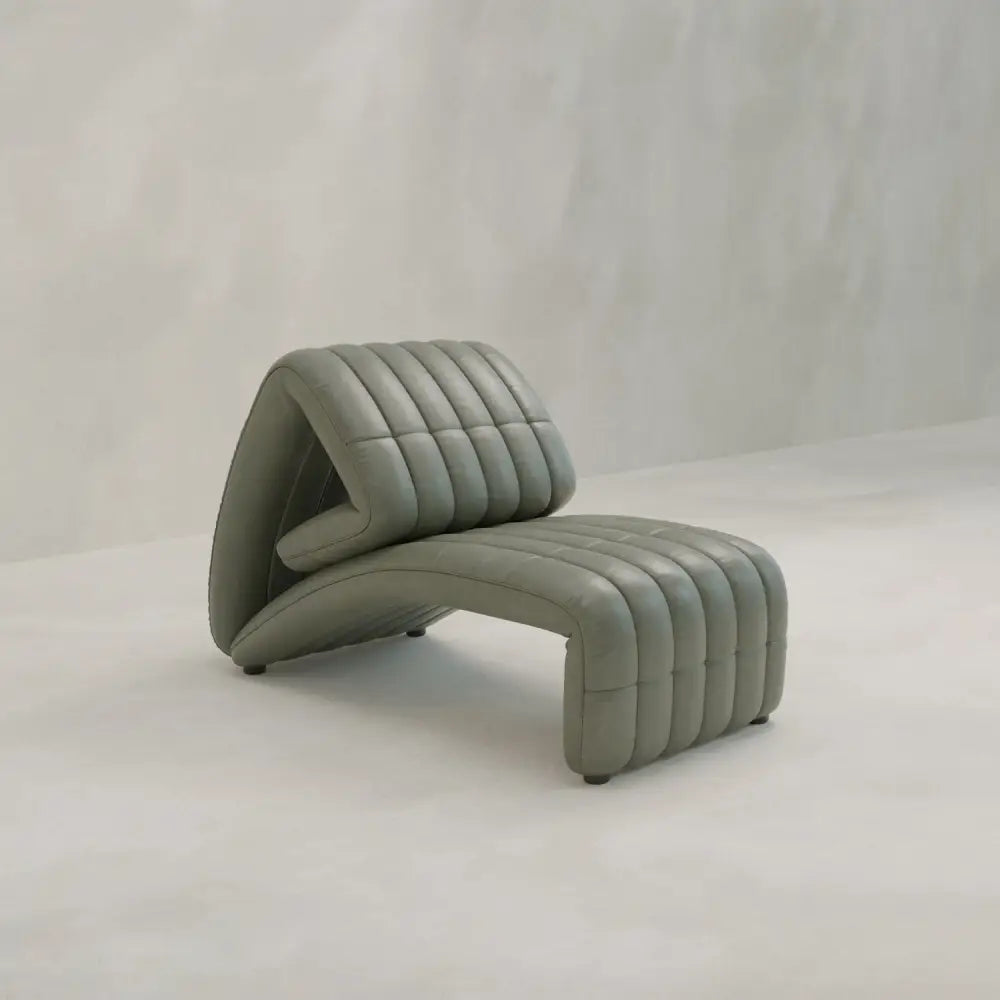 The Hillier Chair is a sculptural lounge chair with ribbed, padded sections, upholstered in premium vintage leather, perfect for a minimalist space with light walls and floors.